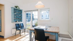 A dining area with a wooden table, black chairs, a blue shelving unit, and a window with blinds. - 4 Star Holiday Home in Ringkobing (Ringkobing)