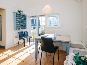 A dining area with a wooden table, black chairs, a blue shelving unit, and a window with blinds. - 4 Star Holiday Home in Ringkobing (Ringkobing)