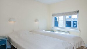 A room with two beds, a window with a view, and a nightstand with a lamp. - 4 Star Holiday Home in Ringkobing (Ringkobing)