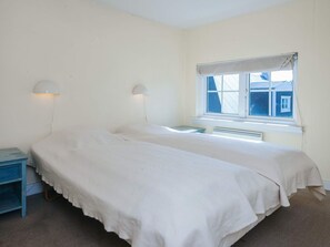 A room with two beds, a window with a view, and a nightstand with a lamp. - 4 Star Holiday Home in Ringkobing (Ringkobing)