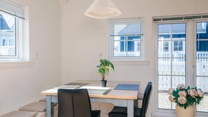 A dining area with a table, chairs, a potted plant, and a hanging light fixture.