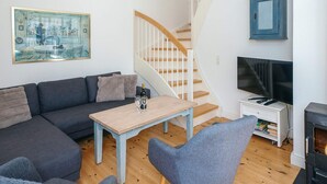 A living room with a sofa, a coffee table, a TV, a fireplace, and a staircase.