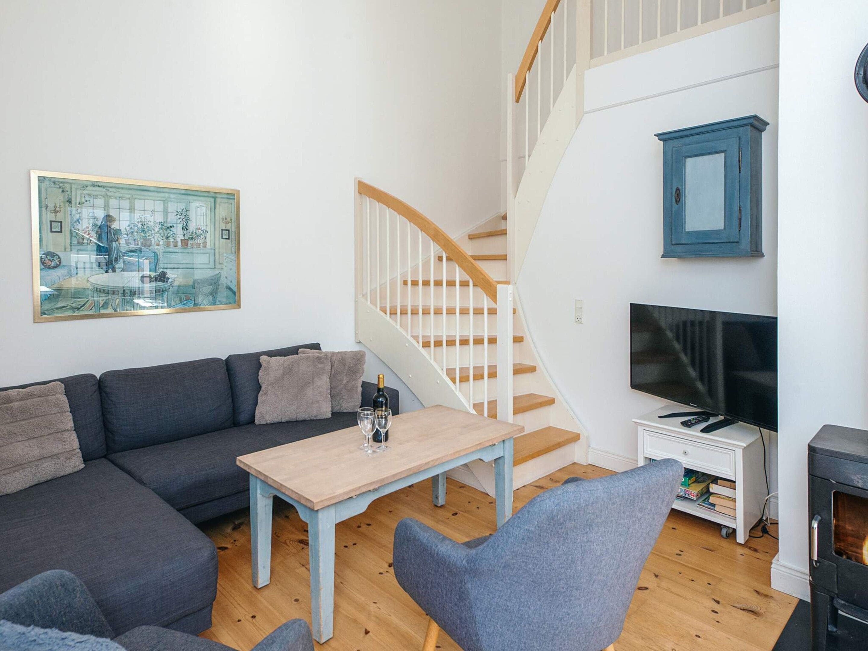 A living room with a sofa, a coffee table, a TV, a fireplace, and a staircase.
