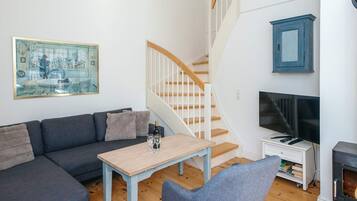 A living room with a sofa, a coffee table, a TV, a fireplace, and a staircase.
