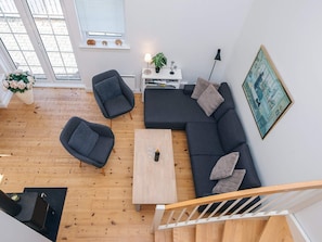 En moderne stue med sofa, stole, sofabord, pejs og trappe.