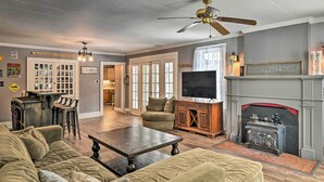A cozy living room with a fireplace, a television, and a dining area with bar stools. - Forestport Home w/ Access to Otter Lake (Forestport)