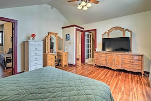 Une chambre à coucher avec un grand lit, une commode en bois et un téléviseur.