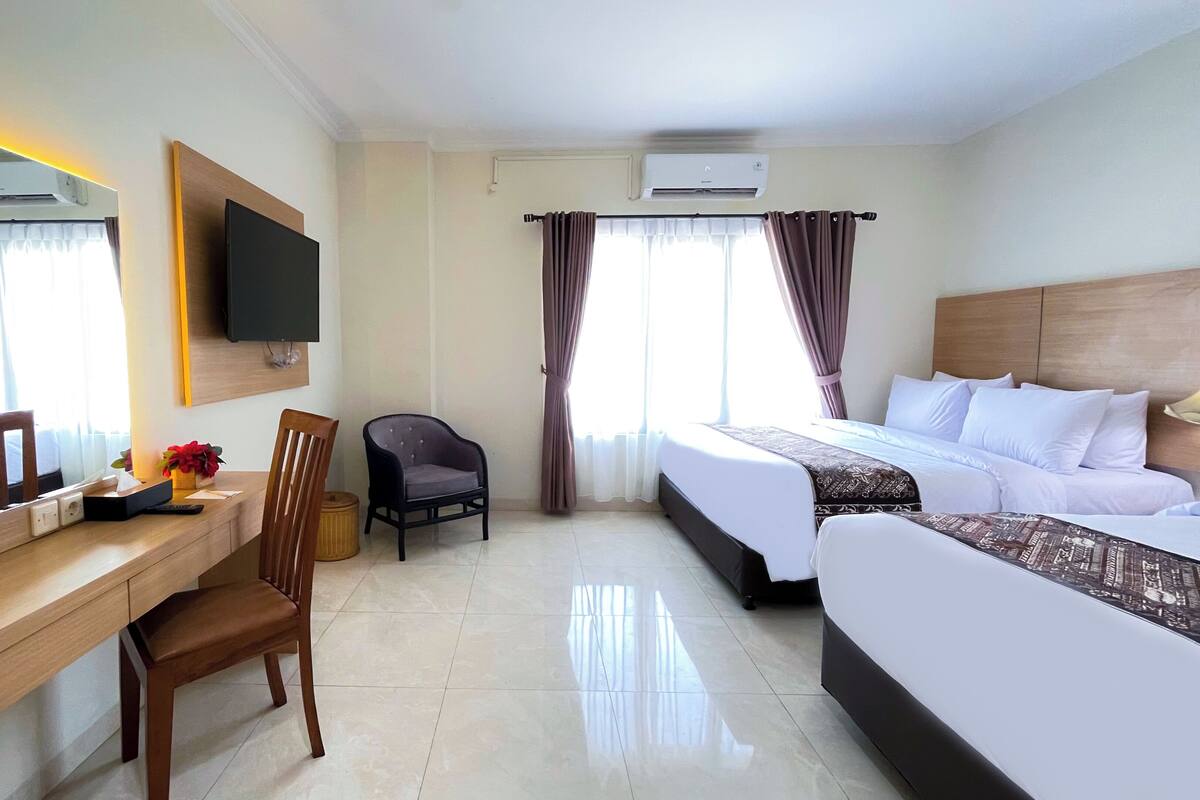 Een hotelkamer met een bed, een bureau met stoel, een televisie en een airconditioning.
