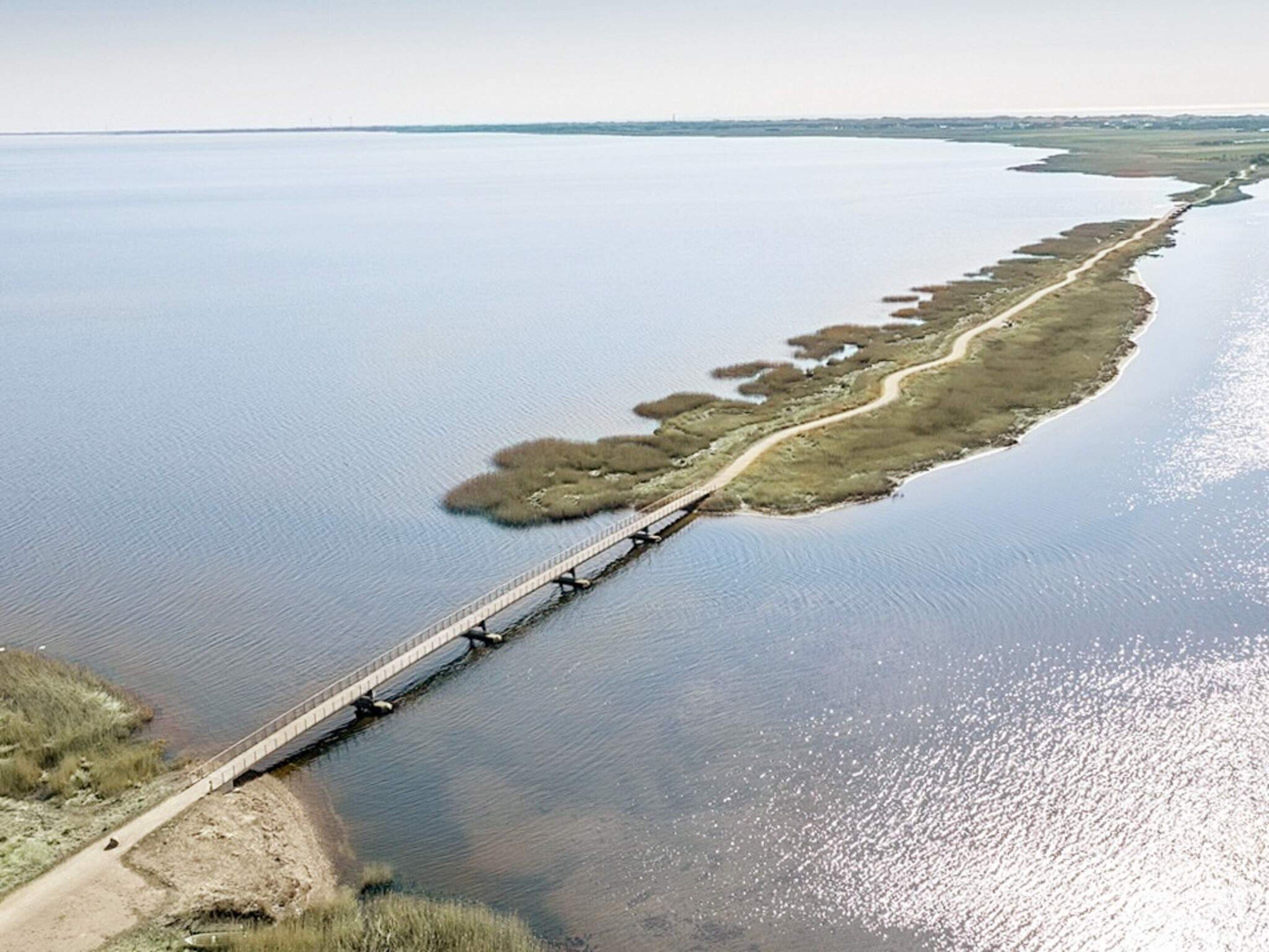Un long pont enjambant une étendue d’eau calme, avec une étroite bande de terre sur un de ses côtés.