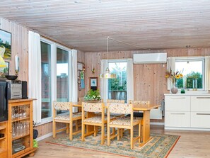 Un comedor con una mesa y sillas de madera, un tapete, y una zona de cocina con armarios y una ventana.