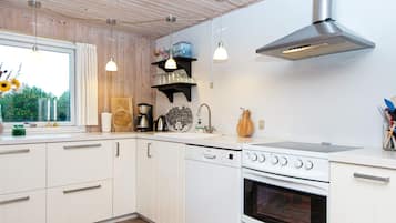 A modern kitchen with white cabinetry, a stainless steel range hood, a built-in oven, and pendant lighting.