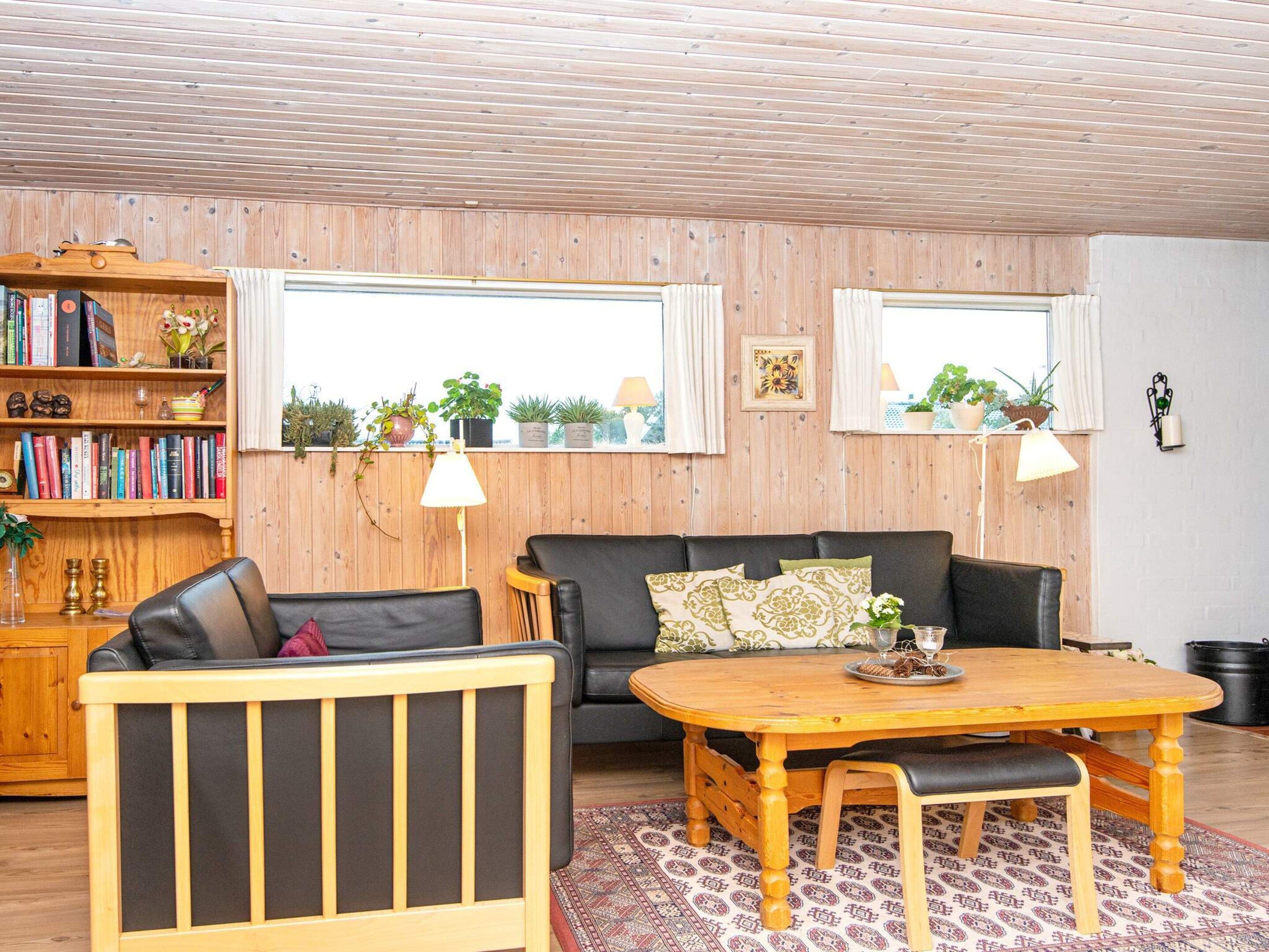 Een gezellige woonkamer met een bank, een houten tafel en een boekenplank vol boeken.