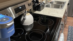Una cocina moderna con estufa negra, electrodomésticos de acero inoxidable y encimera de granito.