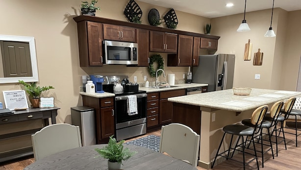 Una cocina moderna con armarios de madera oscura, electrodomésticos de acero inoxidable y una isla central con taburetes de bar.