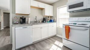 Una cocina moderna con armarios blancos, horno empotrado y encimera con varios electrodomésticos.