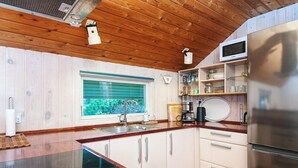 A modern kitchen with wooden cabinets, a stainless steel refrigerator, a built-in microwave, and a window with green blinds. - 6 Person Holiday Home in Glesborg-by Traum (Glesborg)