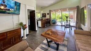 Ein geräumiger Wohnbereich mit einem Couchtisch aus Holz, einer Couch und einem Fernseher, der eine Buddha-Statue zeigt.