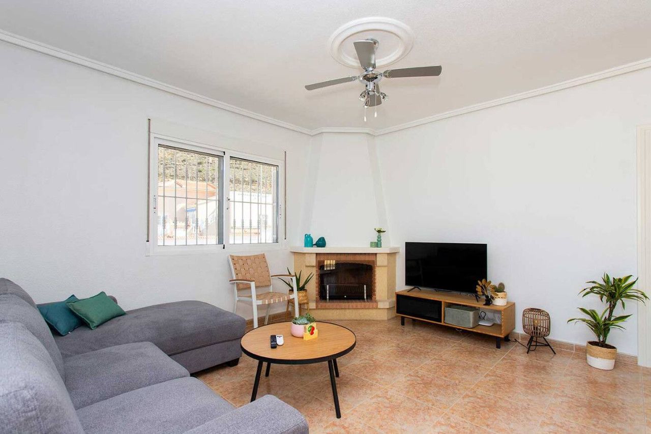 Una sala de estar con un sofá, una mesa de centro, una chimenea, un televisor y un ventilador de techo.