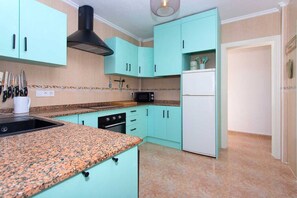 A kitchen with teal cabinets, a microwave, a stove, and a sink. - CH Villa Rio Mundo Rojales (Rojales)