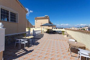 A patio area with outdoor seating, a tiled floor, and a view of the surrounding neighborhood.