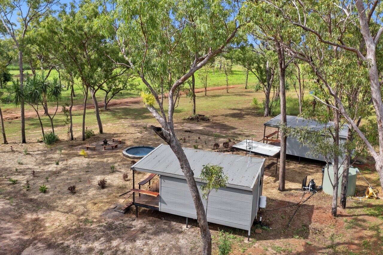 Eine rustikale Holzhütte mit Metalldach, umgeben von Bäumen und einem kleinen Pool.