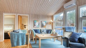 Interior acogedor de una cabaña con paredes de madera, un comedor y una zona de estar con mesa y sillas.