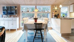 Una cocina moderna con un ventanal grande, techo de madera y un comedor con mesa y sillas.