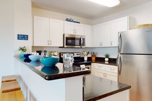 Una cocina moderna con armarios blancos, electrodomésticos de acero inoxidable y encimera de granito.