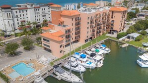 Un puerto deportivo con varias embarcaciones amarradas, una piscina y un edificio de varios pisos con balcones.