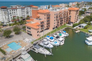 Un puerto deportivo con varias embarcaciones amarradas, una piscina y un edificio de varios pisos con balcones.