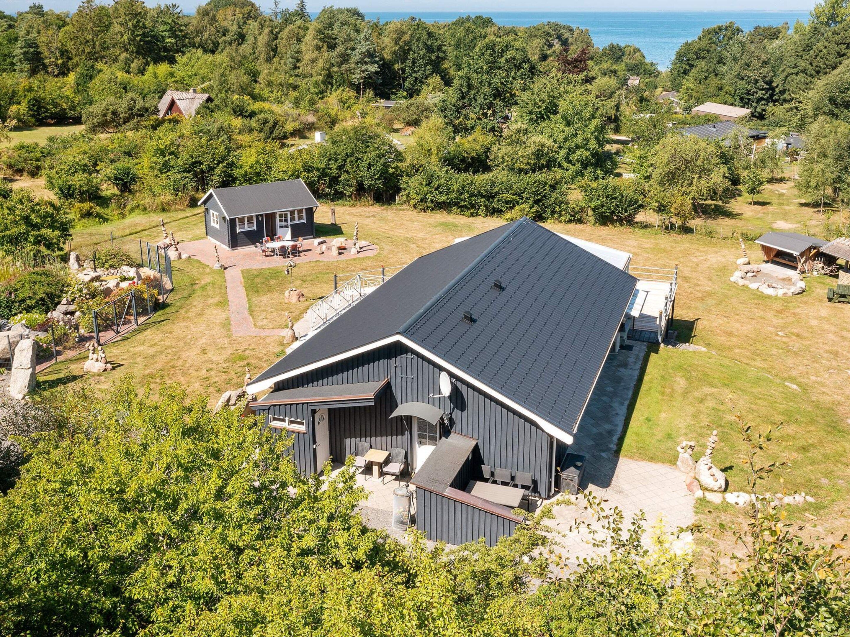 Uma casa moderna com um amplo terraço, rodeada por vegetação exuberante e vista para o mar.