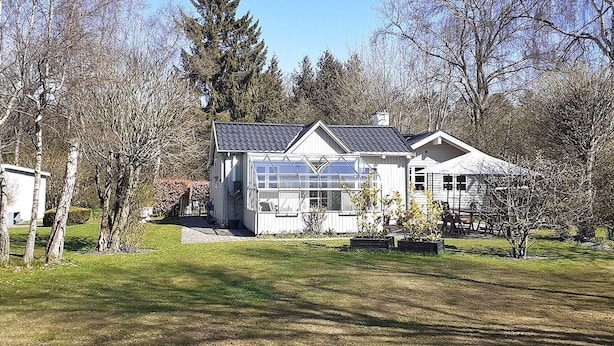 A house with a large glass greenhouse, a covered porch, and a well-maintained lawn. - 6 Person Holiday Home in Taastrup (Taastrup)