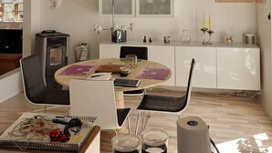 A modern kitchen with a dining area, featuring a round table with chairs, a built-in stove, and a TV mounted on the wall. - 6 Person Holiday Home in Taastrup (Taastrup)