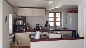 A compact kitchen with white cabinets, a microwave, a coffee maker, and a refrigerator. - 6 Person Holiday Home in Taastrup (Taastrup)
