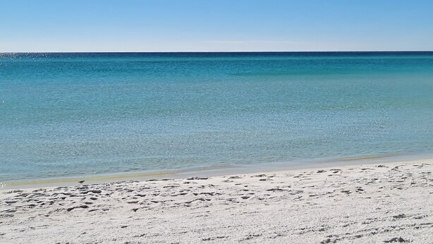 Ein Strand mit klarem türkisblauem Wasser und weißem Sand.