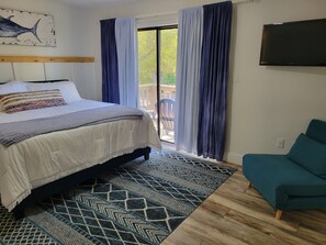 Une chambre avec un lit, une télévision, un canapé et un balcon avec des rideaux.