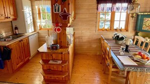 A cozy cabin-style kitchen with wooden cabinets, a dining table with chairs, and a window with curtains. - 6 Person Holiday Home in Hatlestrand-by Traum (Kvinnherad)
