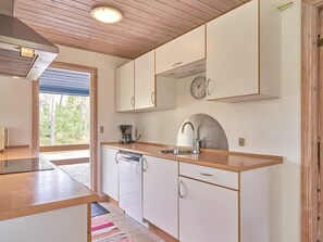 A modern kitchen with wooden cabinets, a stainless steel sink, and a built-in clock.