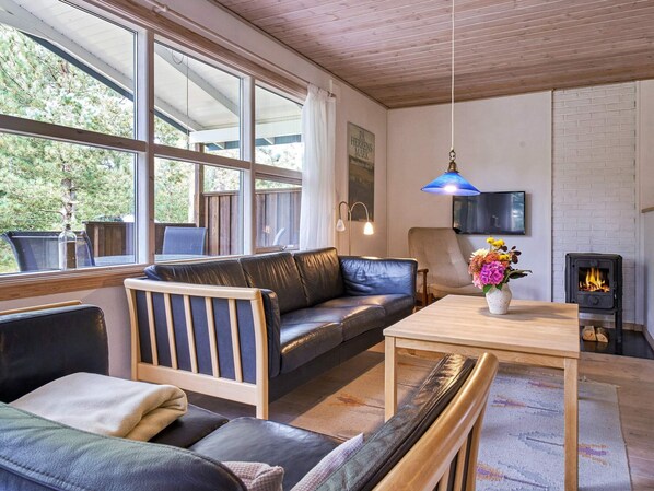 A cozy living room with a leather sofa, a wooden table, and a fireplace.