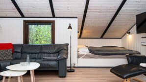 A cozy room with a black leather sofa, a small white table, a black chair, and a bed with a white headboard. - 6 Person Holiday Home in Oksbol-by Traum (Oksbol)