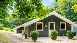 A dark-colored cabin with a sloped roof, a gravel driveway, and three small bushes in front. - 6 Person Holiday Home in Oksbol-by Traum (Oksbol)