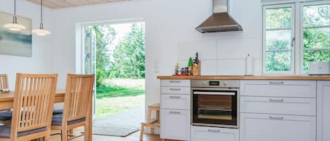 A modern kitchen with white cabinets, a built-in oven, and a large window.