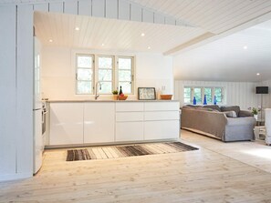 A modern kitchen with white cabinetry, a built-in sink, and a window above the countertop. - 4 Star Holiday Home in Aakirkeby (Akirkeby)