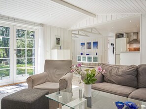 A modern living room with a checkered armchair, a brown sofa, and a glass coffee table with a vase of flowers.