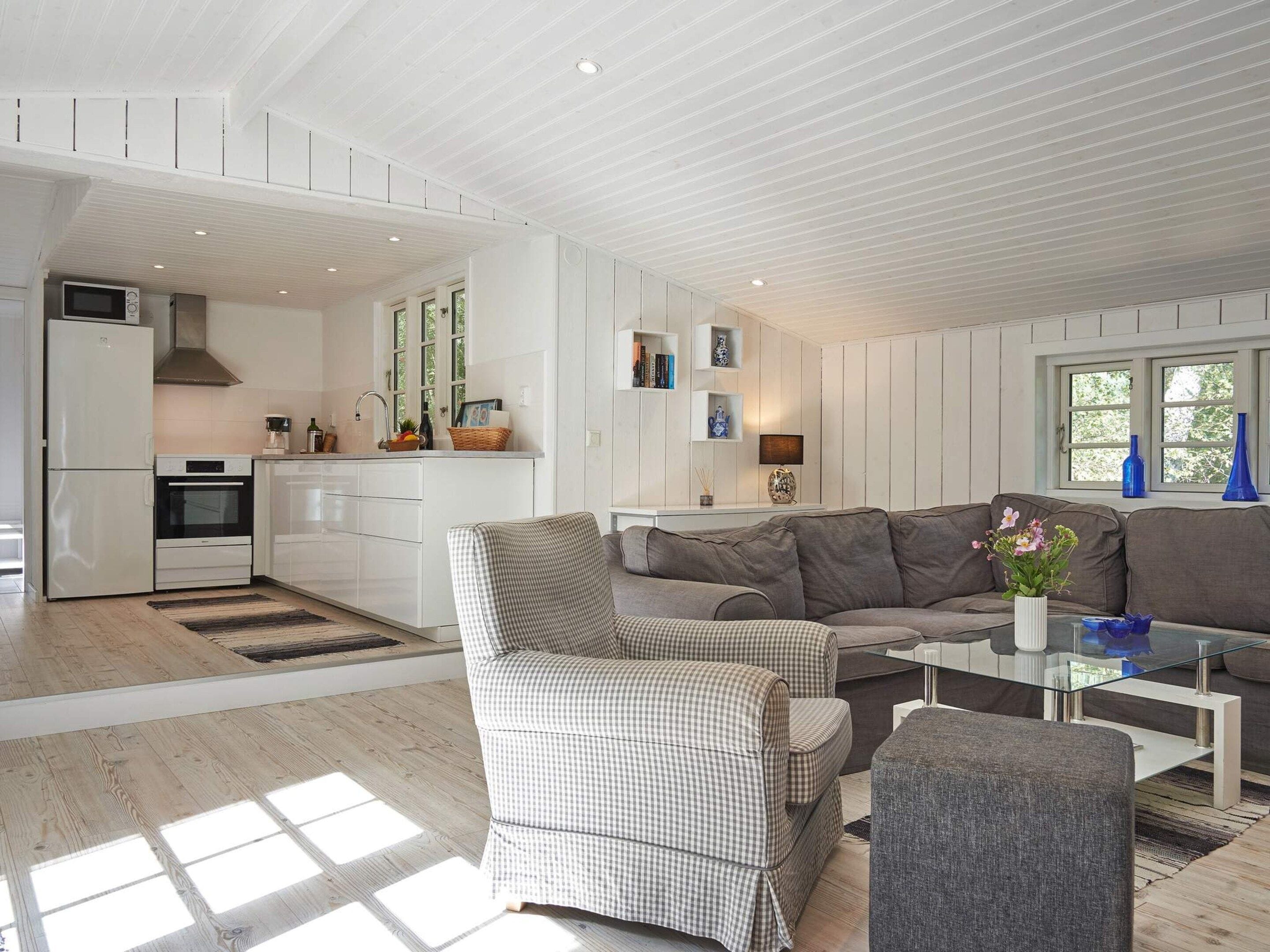 Un espace de vie moderne comprenant une cuisine, un canapé, un fauteuil et une table basse.