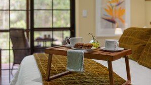 A bed with a quilt, a wooden table with two cups and cookies, and a window with a view of greenery. - Stylish rural retreat on the foothills of Mt. Mee (Moorina)