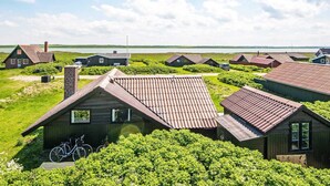 A coastal village with traditional wooden houses, a clear sky, and a view of the sea. - 6 Person Holiday Home in Harboore (Harboore)