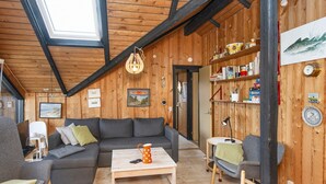 A cozy room with a wooden interior, a sofa, a coffee table, and a bookshelf. - 6 Person Holiday Home in Harboore (Harboore)