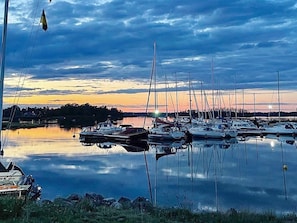 A marina with multiple boats docked, calm water, and a sunset in the background.
