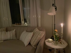 A cozy living room with a sofa, a small table with candles, and a window with curtains. - 4 Person Holiday Home in 38472 (Timmernabben)